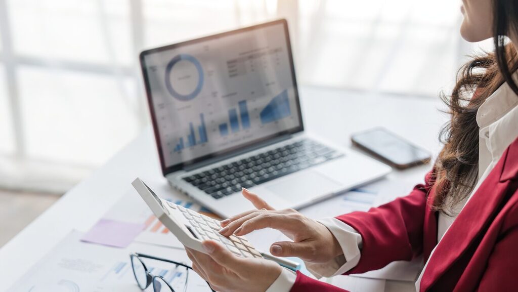 a woman with a calculator at a desk with a computer on it