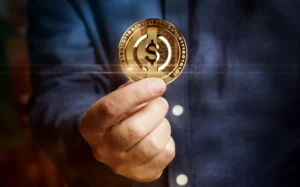 Close-up of a person holding a gold cryptocurrency coin with a dollar sign, symbolizing digital finance and stablecoins